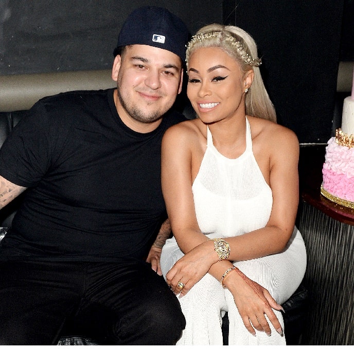 On left Rob Kardashain in black t-shirt sitting next to Blac Chyna on her white dress